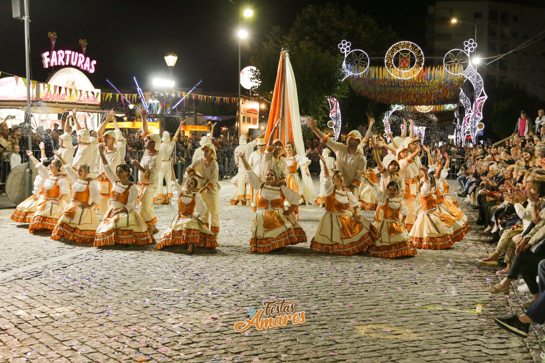 Marcha em trajes laranja e brancos à noite nas Festas d'Amares